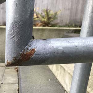 detalj på räcke byggt med färdigalvade rördelar och sedan kallgalvat felaktigt